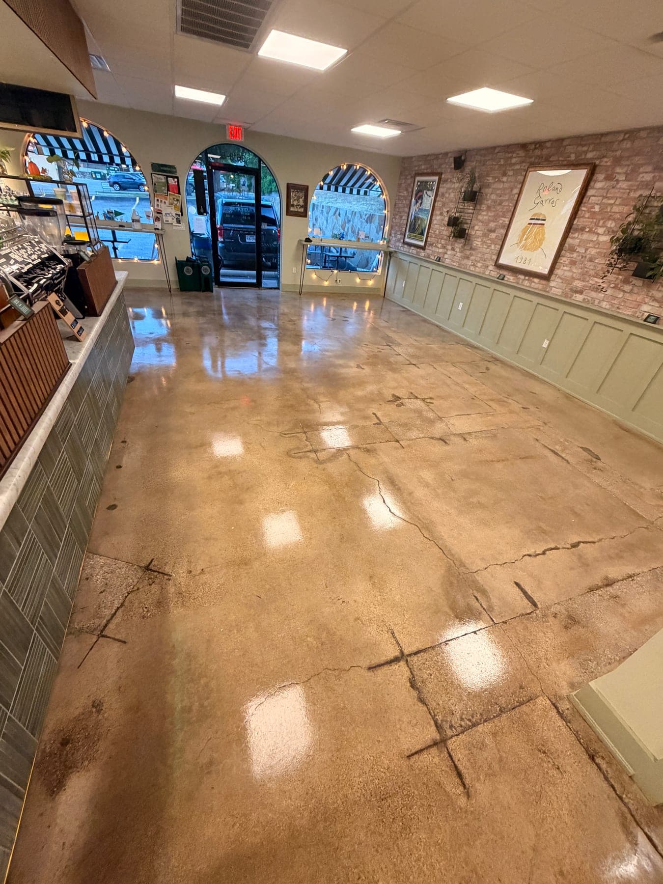 Commercial concrete floor after scrubbing and polishing, reflecting the ceiling lights across the full room