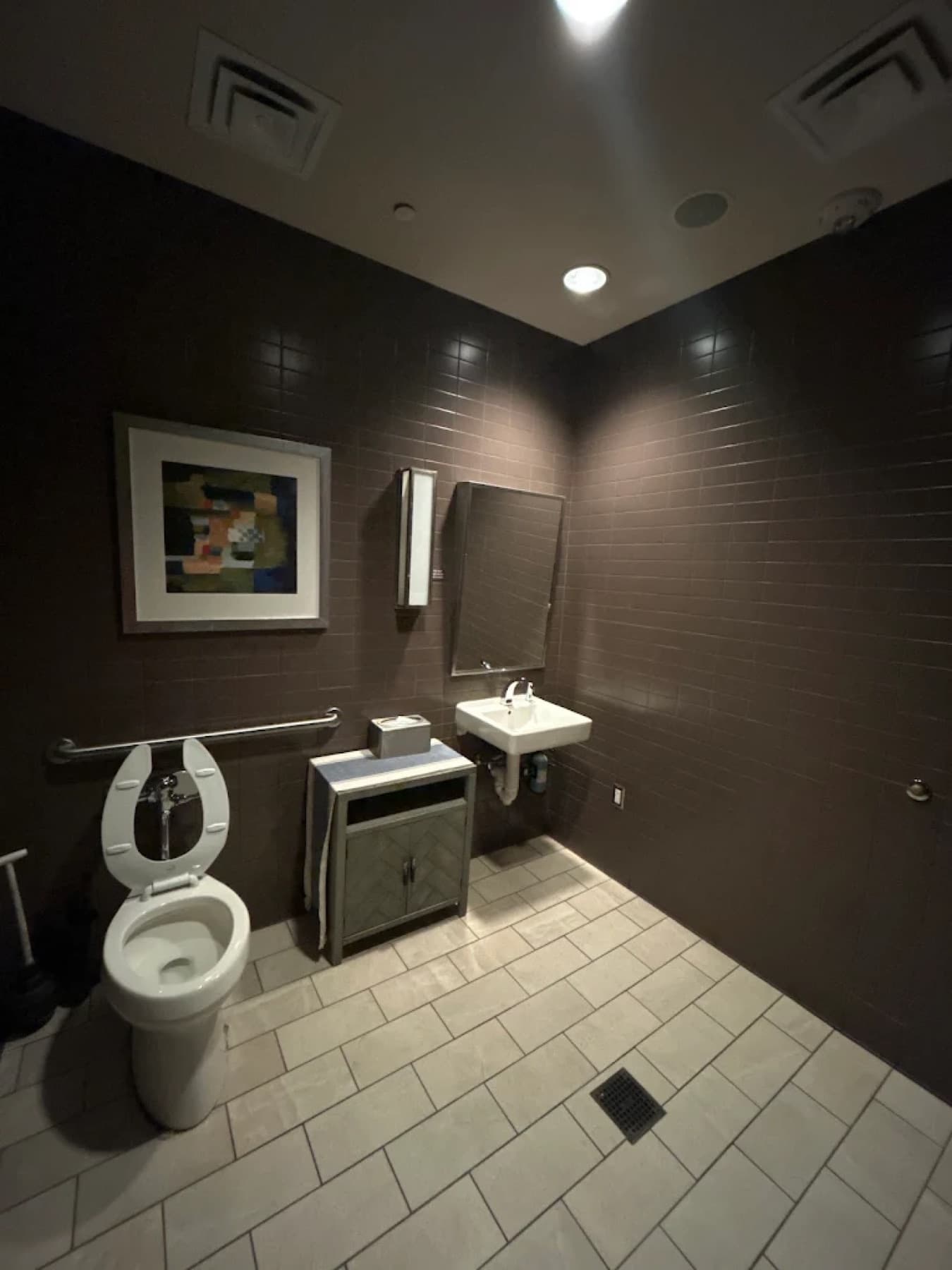 Commercial restroom cleaned and restocked, with mats squared on a wiped tile floor